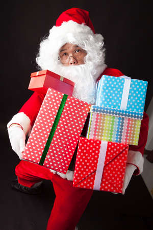 Santa Claus hold many boxes on black  backgroundの写真素材