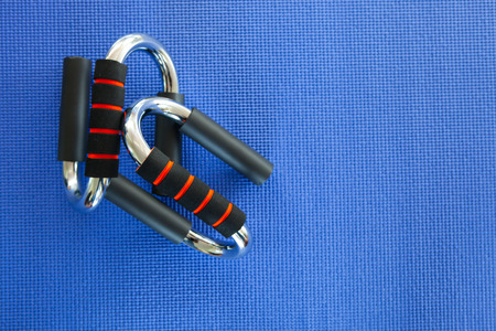 Sports push up bar on yoga blue material background. Weight Training Equipment