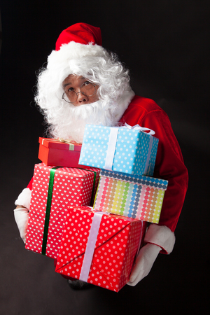 Santa Claus hold many boxes on black  backgroundの写真素材