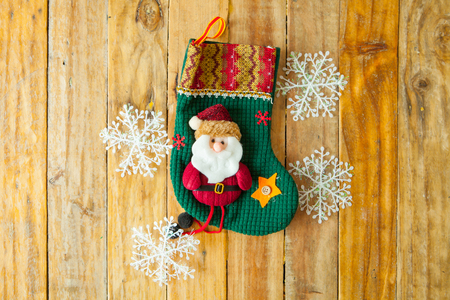 Christmas decoration stocking and snow flake hanging over rustic wooden backgroundの写真素材
