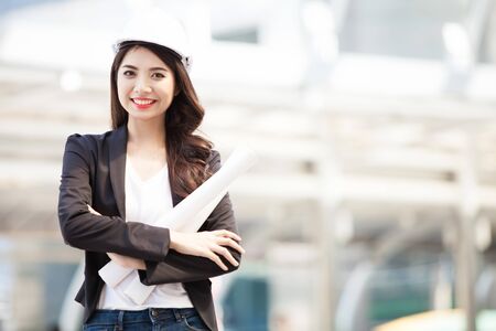 Smiling architect business woman with blueprints isolated portrait. Protect helmet.の写真素材