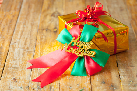 Golden gift box and red ribbon and Happy new year gift on wood background with space.の写真素材