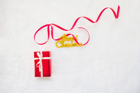 small red gift box and gold merry christmas text with red ribbonの写真素材