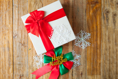 White gift box and red ribbon  on wood background with space.の写真素材