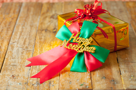 Golden gift box and red ribbon and Happy new year gift on wood background with space.の写真素材