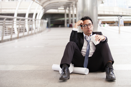 Stressful businessman or engineer sitting outdoor thoughtful thinking with hopelessの写真素材