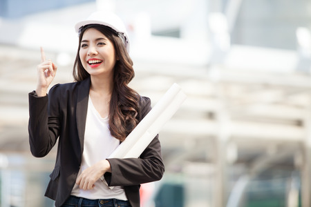 Smiling architect business woman with blueprints isolated portrait. Protect helmet.の写真素材