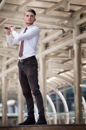 Businessman playing golf with cityscape on the backgroundの写真素材