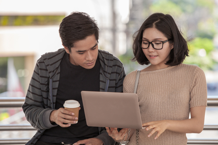 Two students studying with computer notebook outdoorsの写真素材