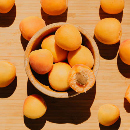  Orange apricots in a wooden round plate on a wooden background. Ripe apricots in summerの写真素材