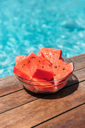 Round plate with watermelons near the pool on the plank floor. Summer concept.の写真素材