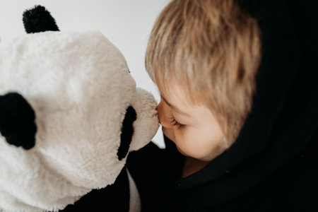 The portrait of cute boy playing with panda toy at home. Favourite toy. Black and white colours....