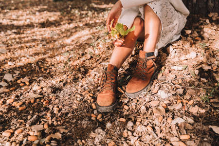 Feet in boots under an oak tree. Spring, autumn. Blue sky with clouds.