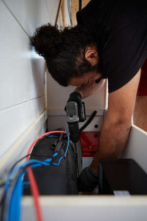 mechanic screwing camper van with electric screwdriver. installing second battery inside a camper...