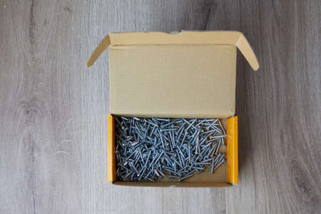 Self tapping screws in a corrugated cardboard box on wood backgroundの写真素材