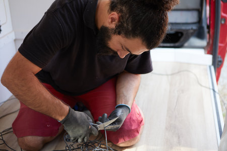 Man cutting cable for electrical equipment inside a camper van