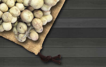 Longkong Thai fruit on brown sackcloth and black wood background.の写真素材