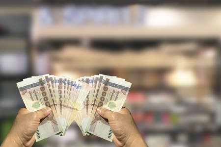 Two hands hold money on blur background.