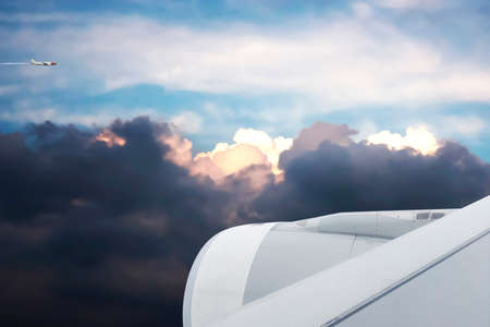 Beautiful view from the plane seeing Sunset sky with storm clouds and another aircraft fly by.の写真素材