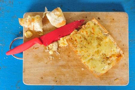 Top view garlic bread with red knife on the chopping block 