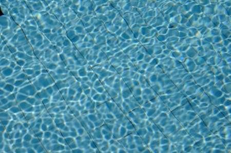 Blue ripped water in swimming pool with sunny reflections