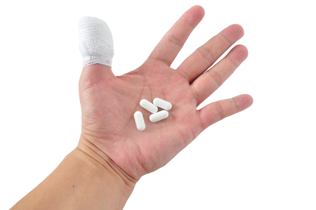 Medicines pill in hand with thumb bandage の写真素材