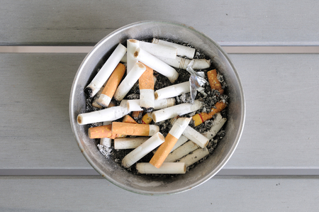 cigarettes in aluminium ashtray on wooden table.の写真素材