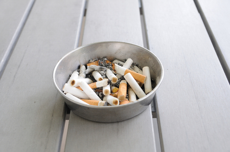 cigarettes in aluminium ashtray on wooden table.の写真素材