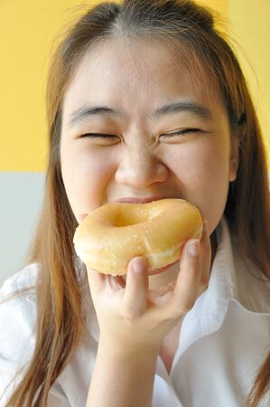 Asian business woman 28 years old in uniform eating plain donut. junk food.の写真素材