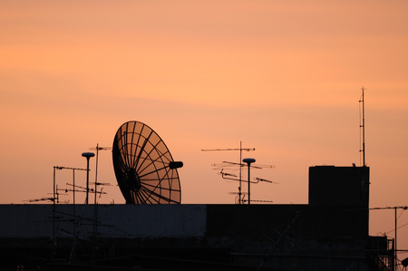 Satellite dish on top building during sunset timeの写真素材