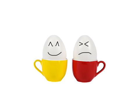 Happy and sad eggs in small color cup