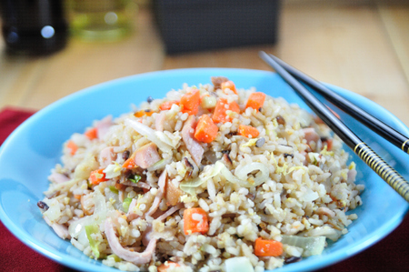 Chicken ham fried rice with carrot in blue plate set up on table, food stylist.の写真素材