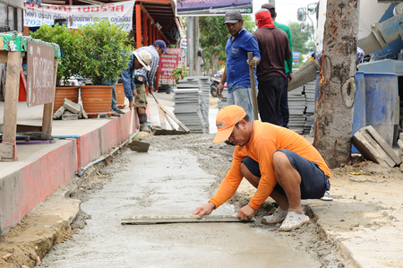 BANGKOK, THAILAND - May 30, 2016: Unidentified workers poured and adjust concrete sidewalk at Bangkok, Thailand.のeditorial素材