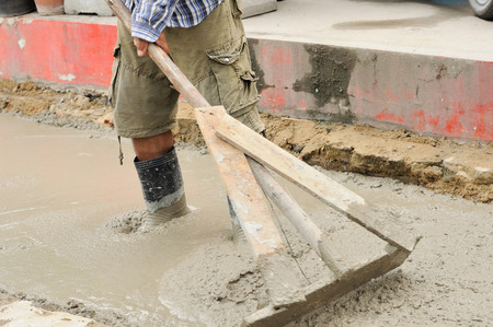 Workers poured and adjust concrete sidewalkの写真素材