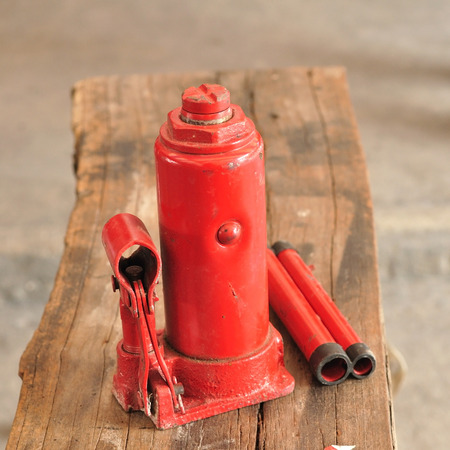 Red car hand jack lay on old wooden plank.の写真素材