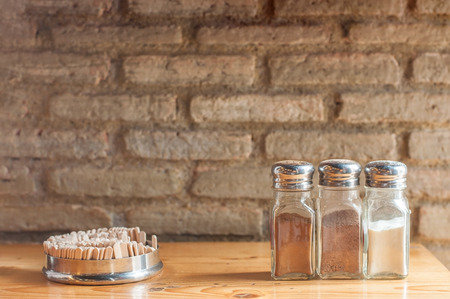 Three bottles of coffee ingredients on wooden bar with grunge brick block wall.の写真素材