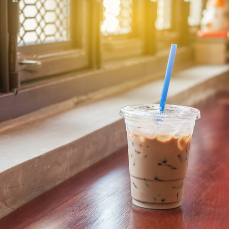 Ice coffee on long wooden bar next to vintage windowsの写真素材