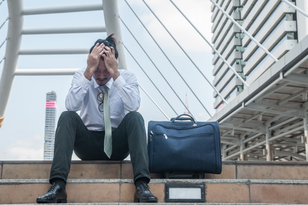 Desperate failure middle Asian business man sat down midst building city.の写真素材
