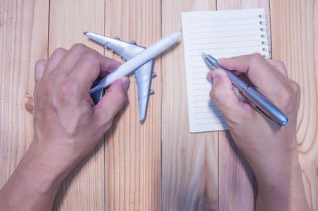 Unidentified man hand writing planning and working with airplane model.の写真素材