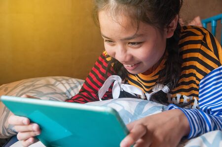 Lifestyle of Caucasian Asian teenager using digital tablet in her house.の写真素材