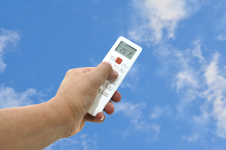 Man had use white air condition remote control point up to blue sky. 25 degree Celsius preventive from Global warming.の写真素材