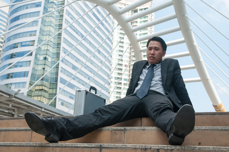 Middle Asian business man be tired failure and desperate sat down midst building city.の写真素材