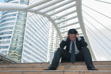 Middle Asian business man be tired failure and desperate sat down midst building city.の写真素材