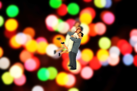 Selective focus miniature couple lover jumping to hug with blur colorful bokeh backgroundの写真素材