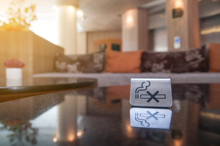 Do not smoke stainless sign lay on glass table with big sofa and pillow in big roomの写真素材