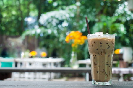 Rest time with glass ice of coffee with green park and orange cosmos background.の写真素材