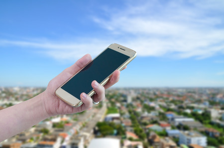 Unidentified hand use smartphone with Cityscape bird eye view with blue sky, Bangkok Thailand.の写真素材
