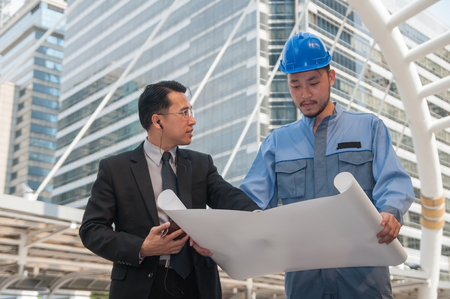Business manager discussing with project engineer with floor plan in site area.の写真素材