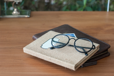 Double notebook traveling book lay on wooden table with black classic eye glasses.の写真素材
