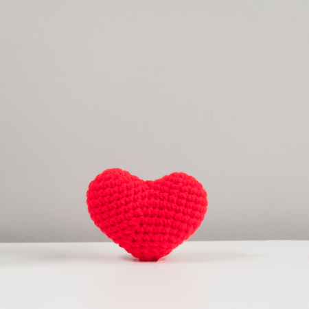 Red wool heart with white wings lay on white table with grey background, valentine love concept.の写真素材